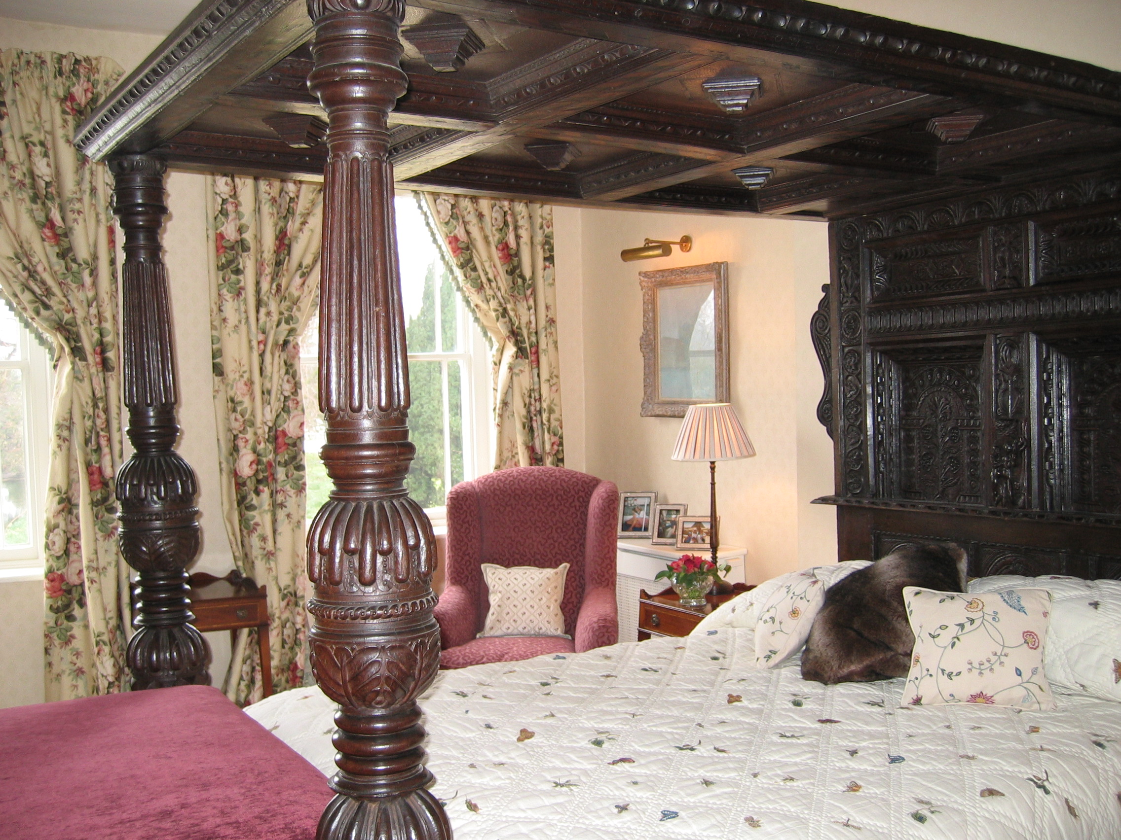 A velvet covered chair, linen curtains, embroidered cotton bedspread all work together to balance the antique four poster bedframe.