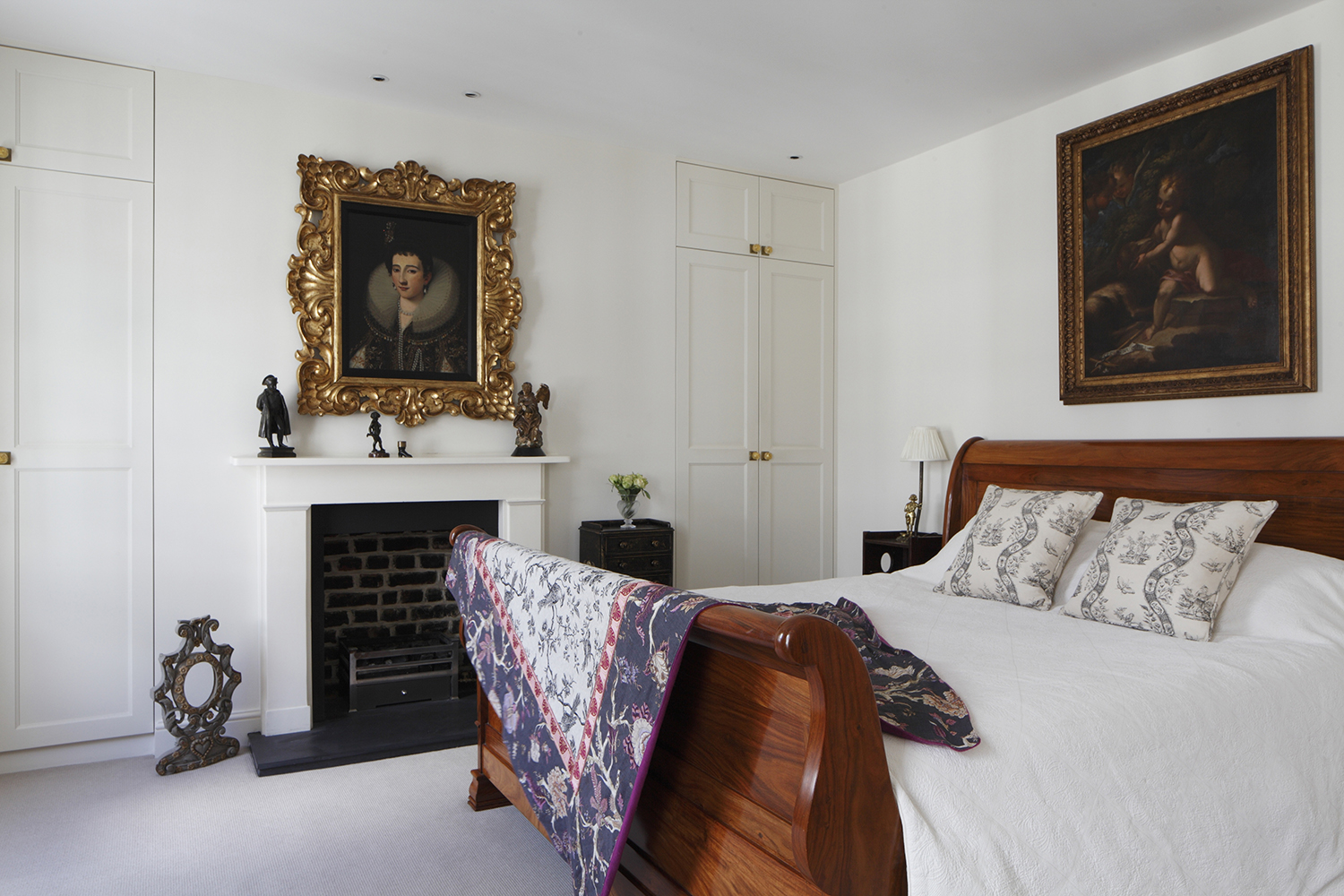 A calm off-white bedroom styled with a coloured vintage bed throw.