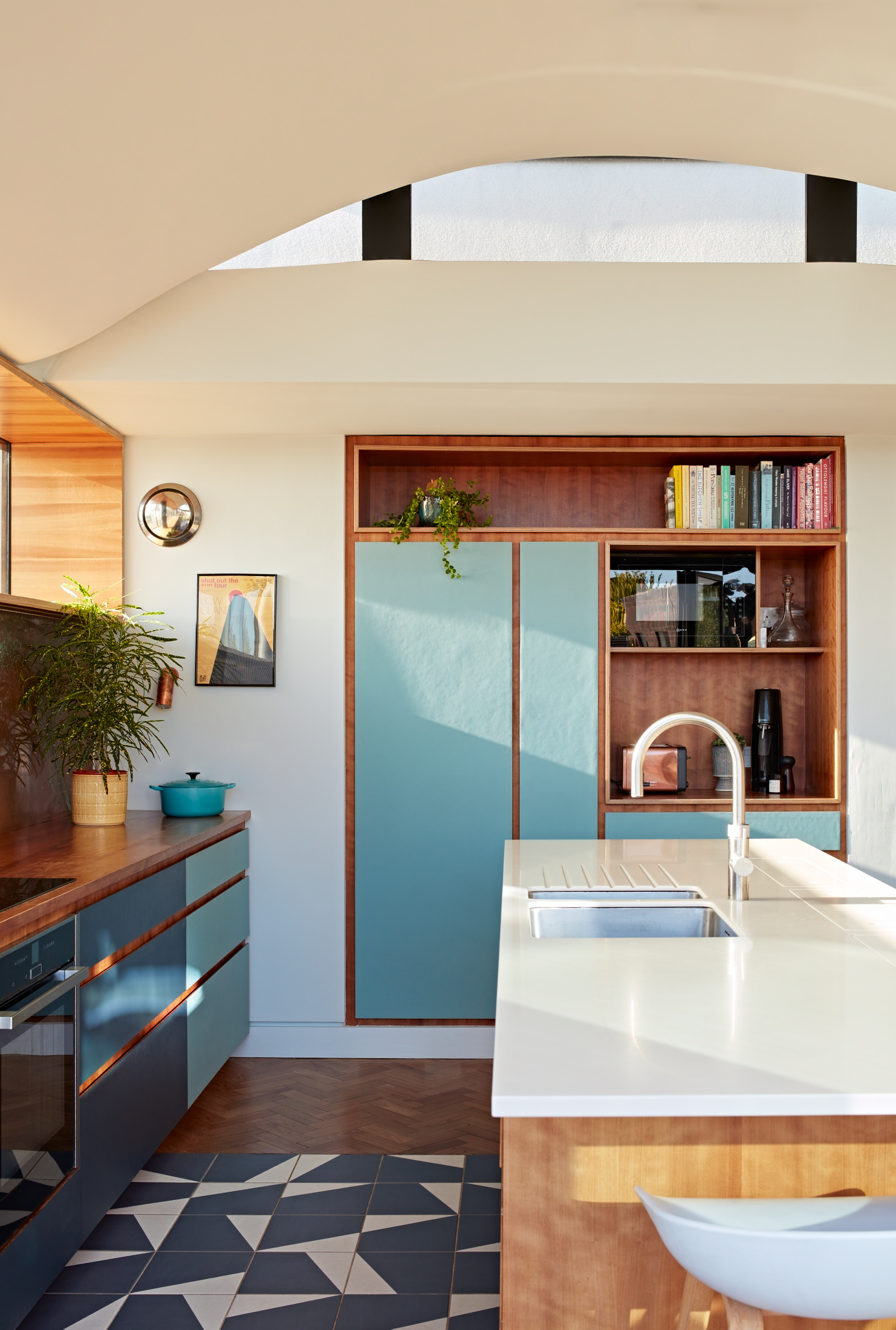 Bespoke cherry kitchen with linoleum drawer fronts and contrasting graphic floor tiles.