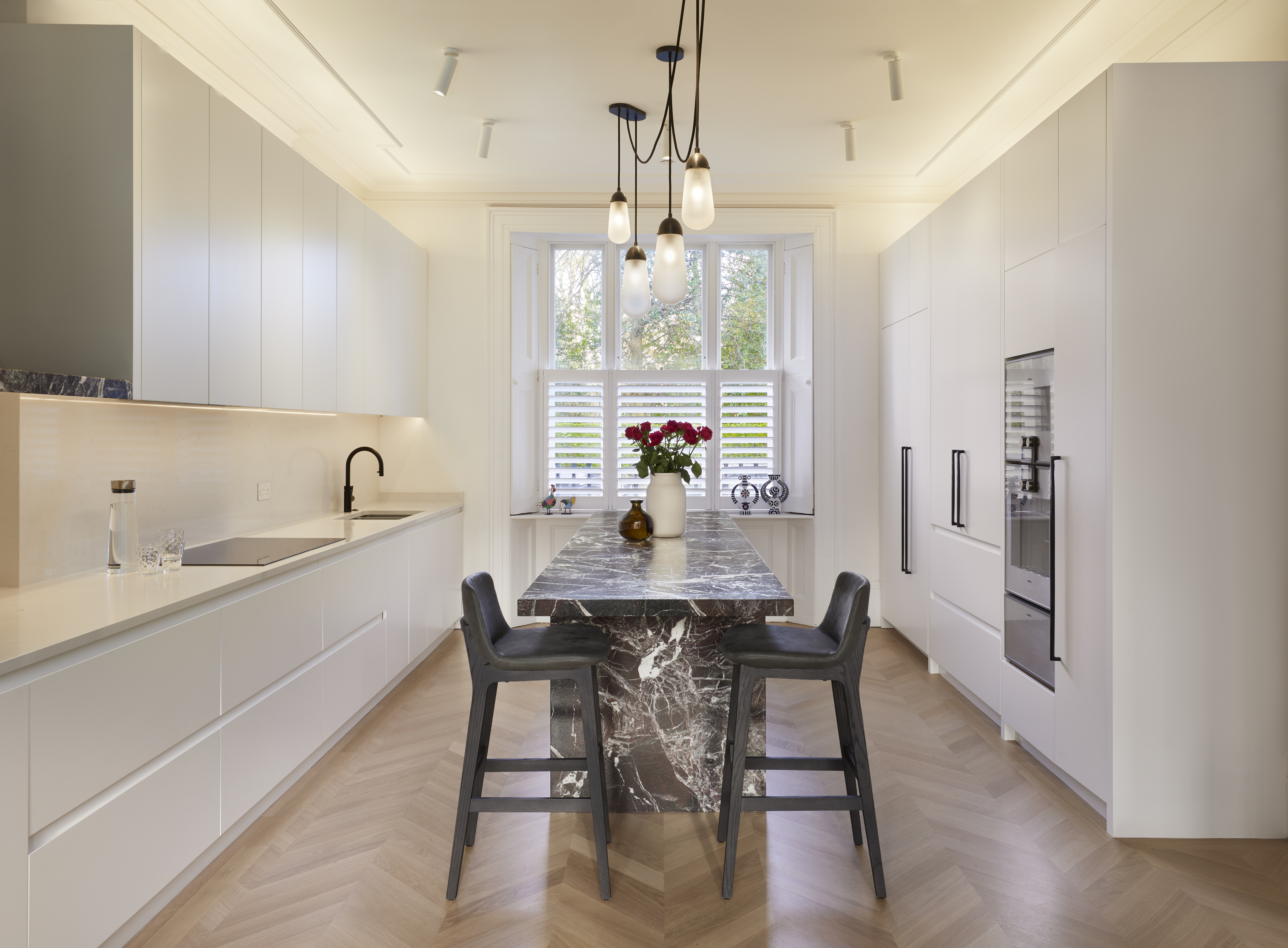 A kitchen with white cabinets & a red & white marble island 