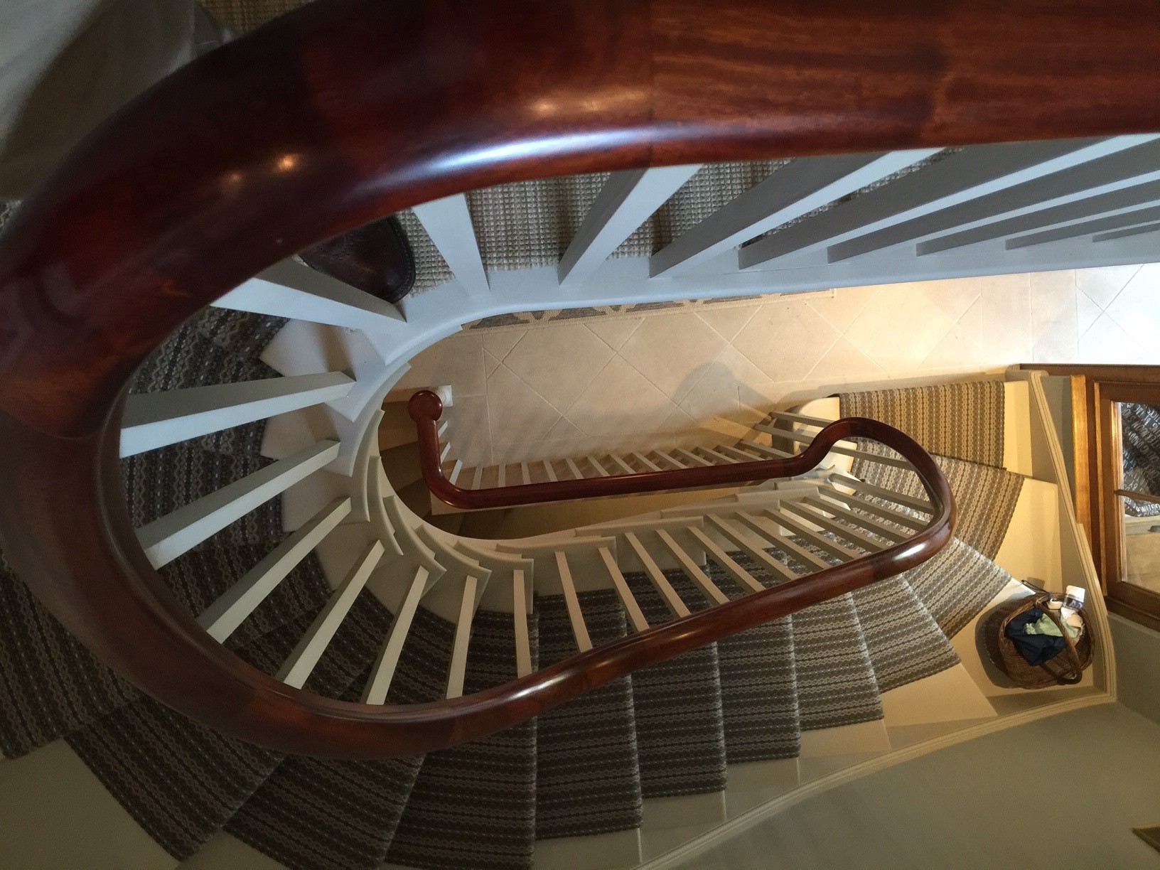 A view down through a Georgian style white painted with a carpet runner, polished mahogany hand rail.