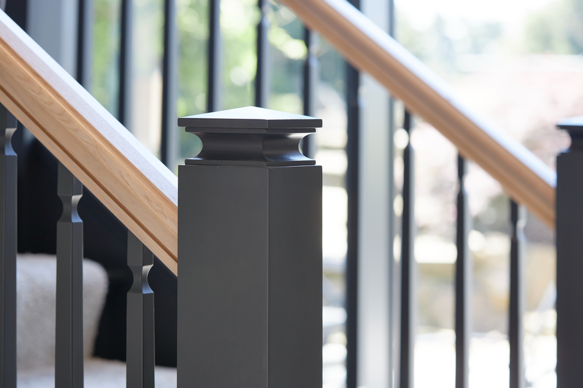 A detail view of a classic contemporary style staircase painted in dark grey with a handrail in natural oak.