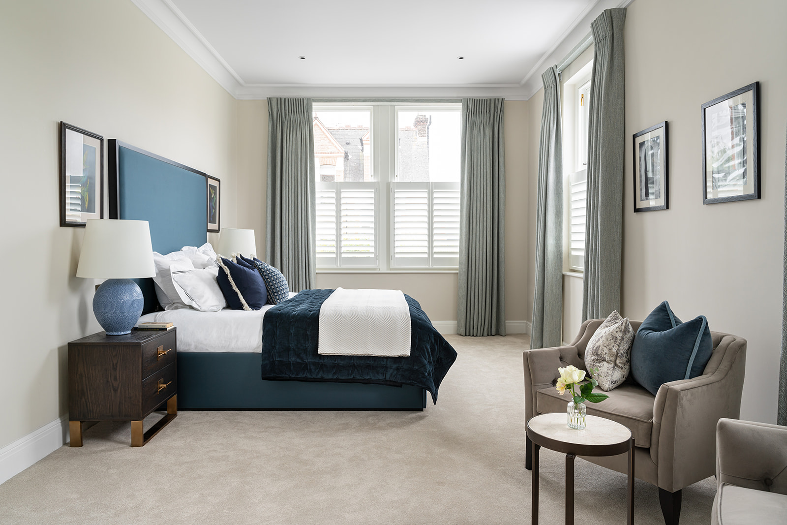 Spacious Luxury Bedroom/Principal Suite with Natural Light – Bright and airy bedroom interior with plush furnishings, a statement blue bed frame, neutral-toned carpet, and elegant window treatments. The refined aesthetic enhances comfort and sophistication in this fully refurbished Barnes home.