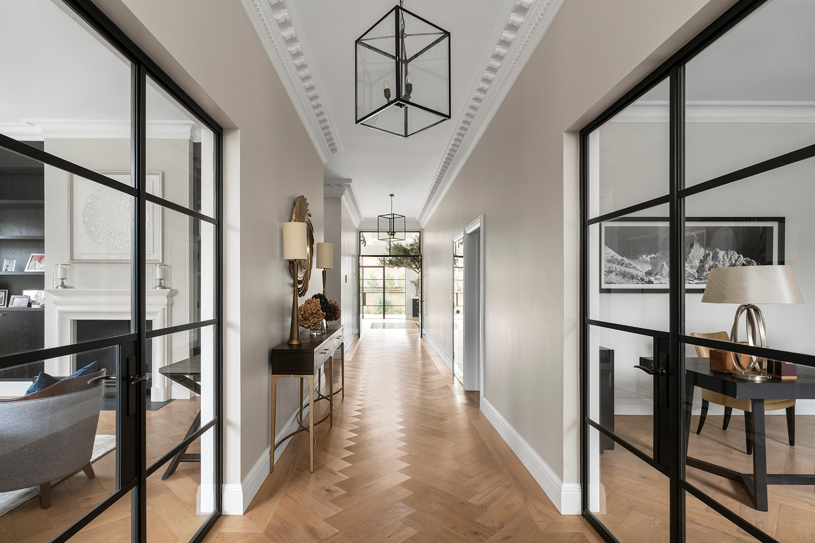 Luxurious Entrance Hall with Crittall-Style Doors in Barnes Home – A grand entrance hall featuring elegant parquet flooring, black steel-framed glass doors, and sophisticated decor in a redefined family home on one of Barnes’ most prestigious boulevards.