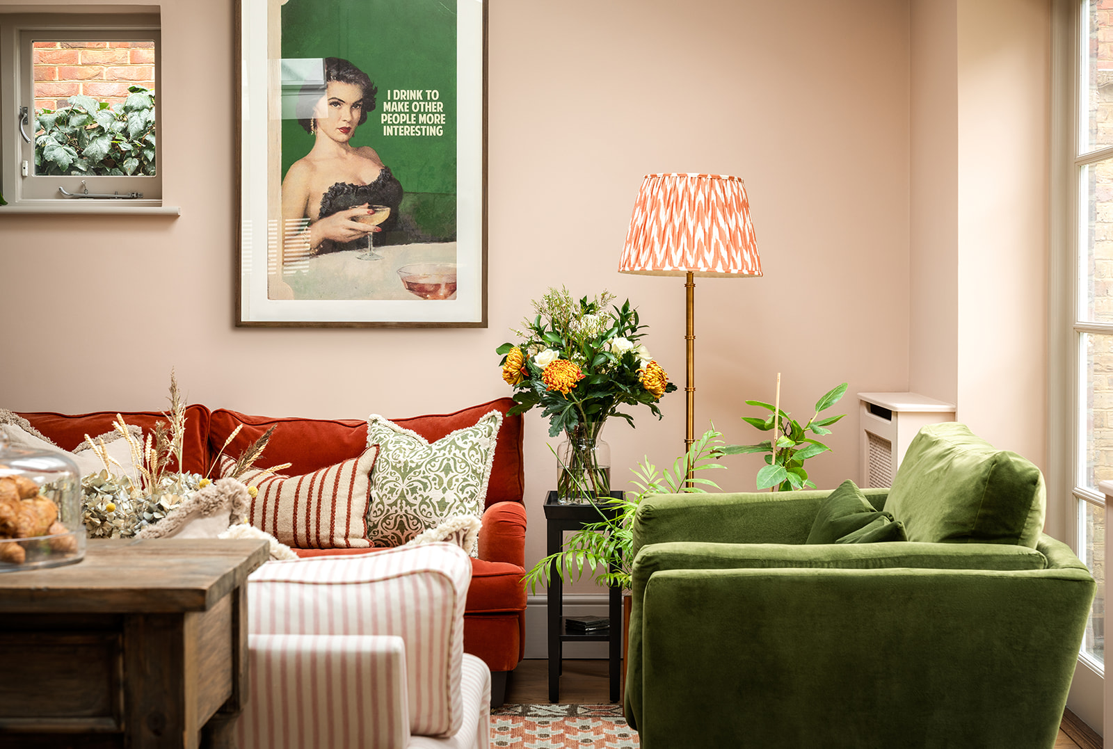 Bright and inviting open plan living room painted in Farrow and Ball’s Setting Plaster, with plush velvet seating, patterned textiles, and a mix of warm terracotta and deep green tones, creating a cosy yet sophisticated space.