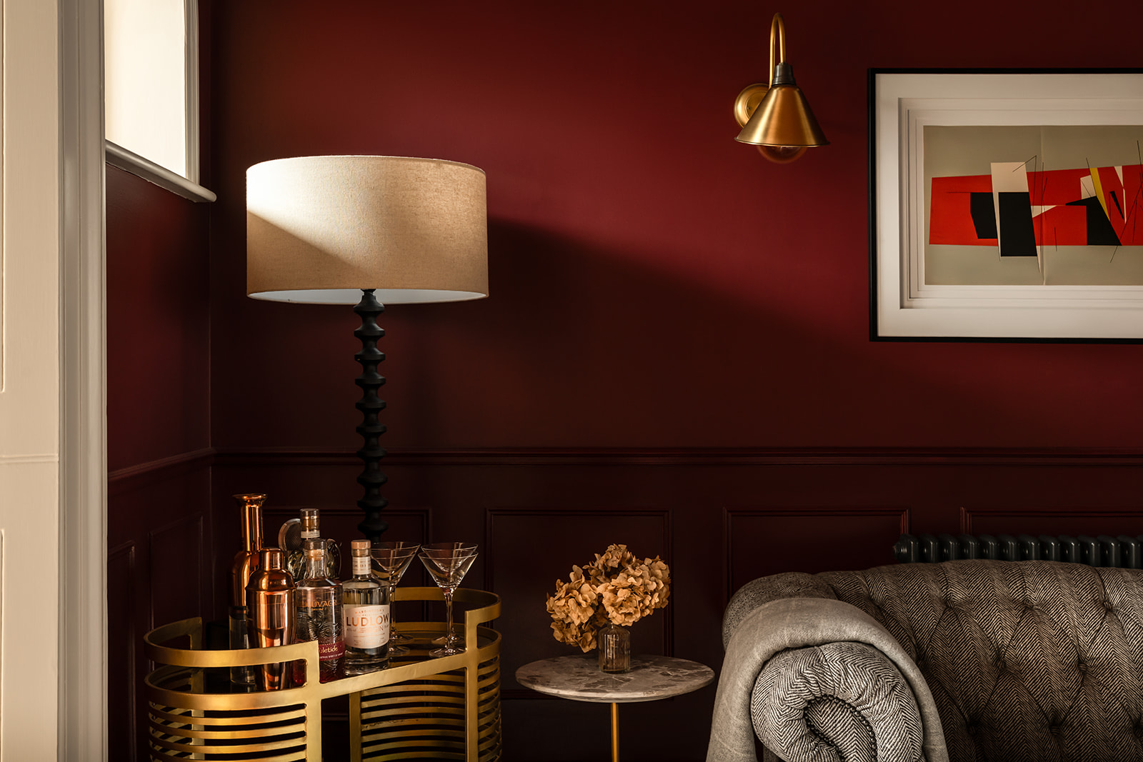 Sophisticated snug colour drenched in Farrow & Ball’s Preference Red, modern artwork, and soft ambient lighting. A cosy, intimate space with rich textures and stylish furniture.