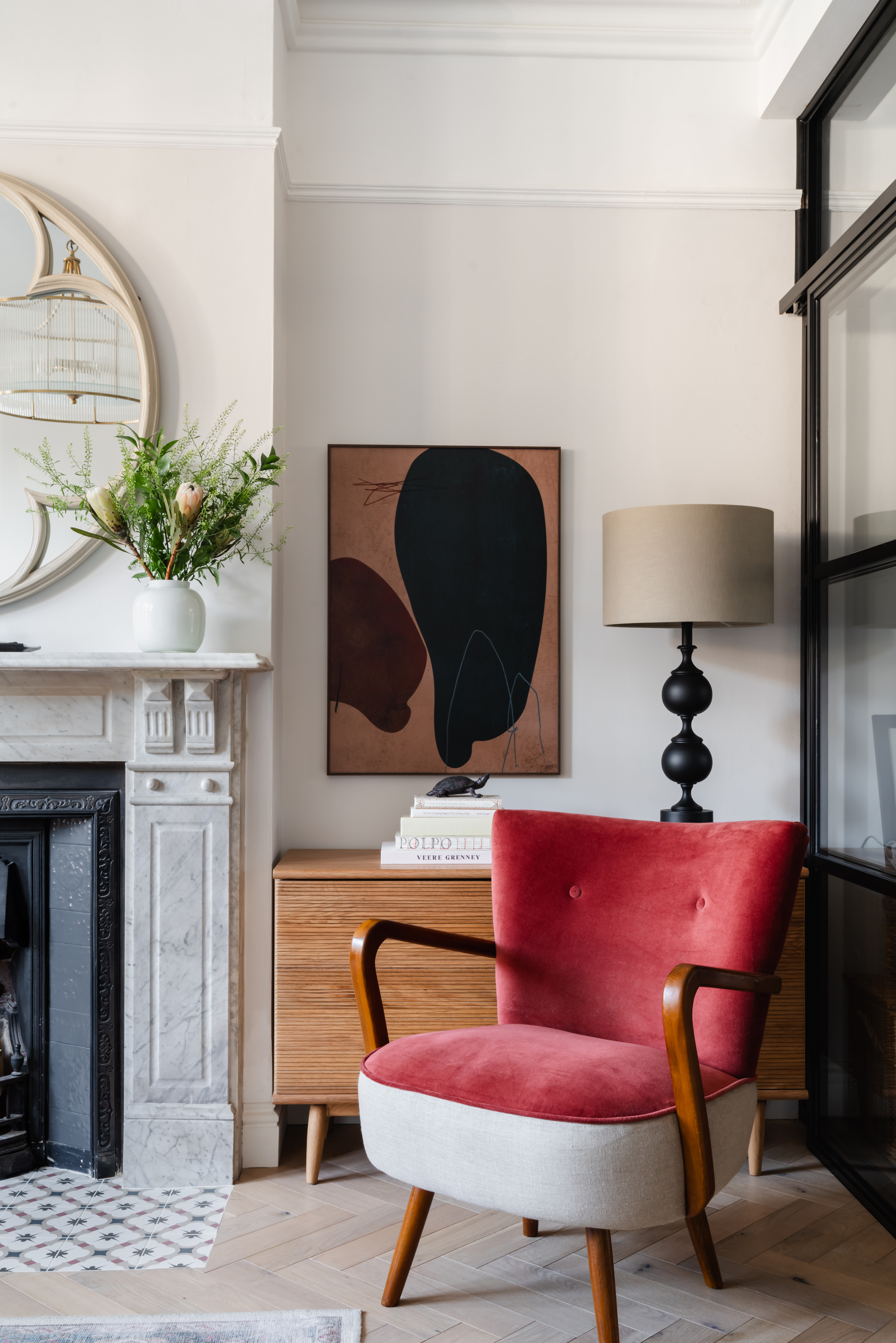 Mid-century modern terracotta velvet armchair (Atkin &amp; Thyme) paired with contemporary abstract artwork, creating a sophisticated reading corner.