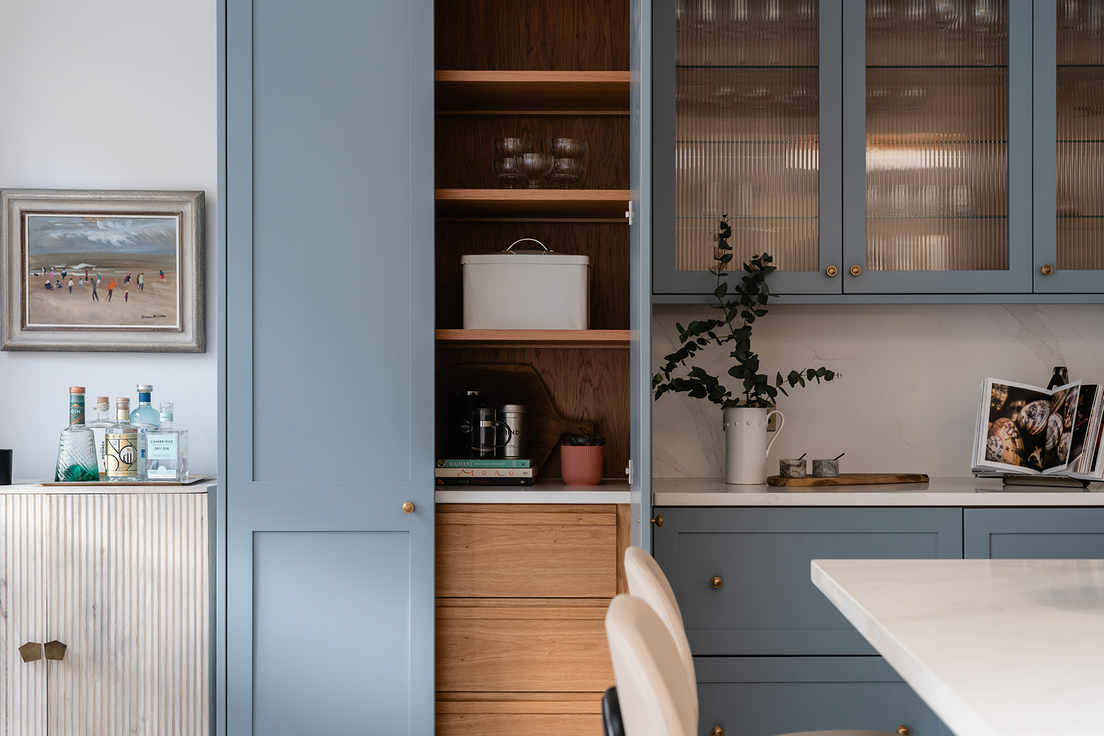 Beautifully designed open pantry with blue cabinetry and warm oak shelving, creating a functional yet aesthetically pleasing storage solution.