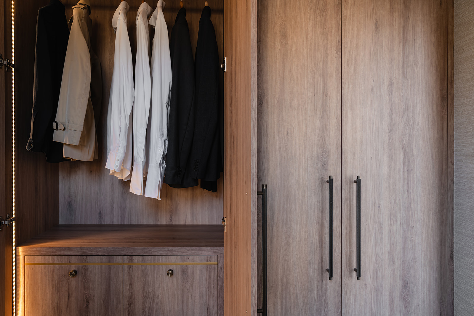 A bespoke oak veneer wardrobe interior featuring custom shelving with brass trim, soft LED inset lighting, and carefully curated storage. A refined and practical space for an organised dressing area.