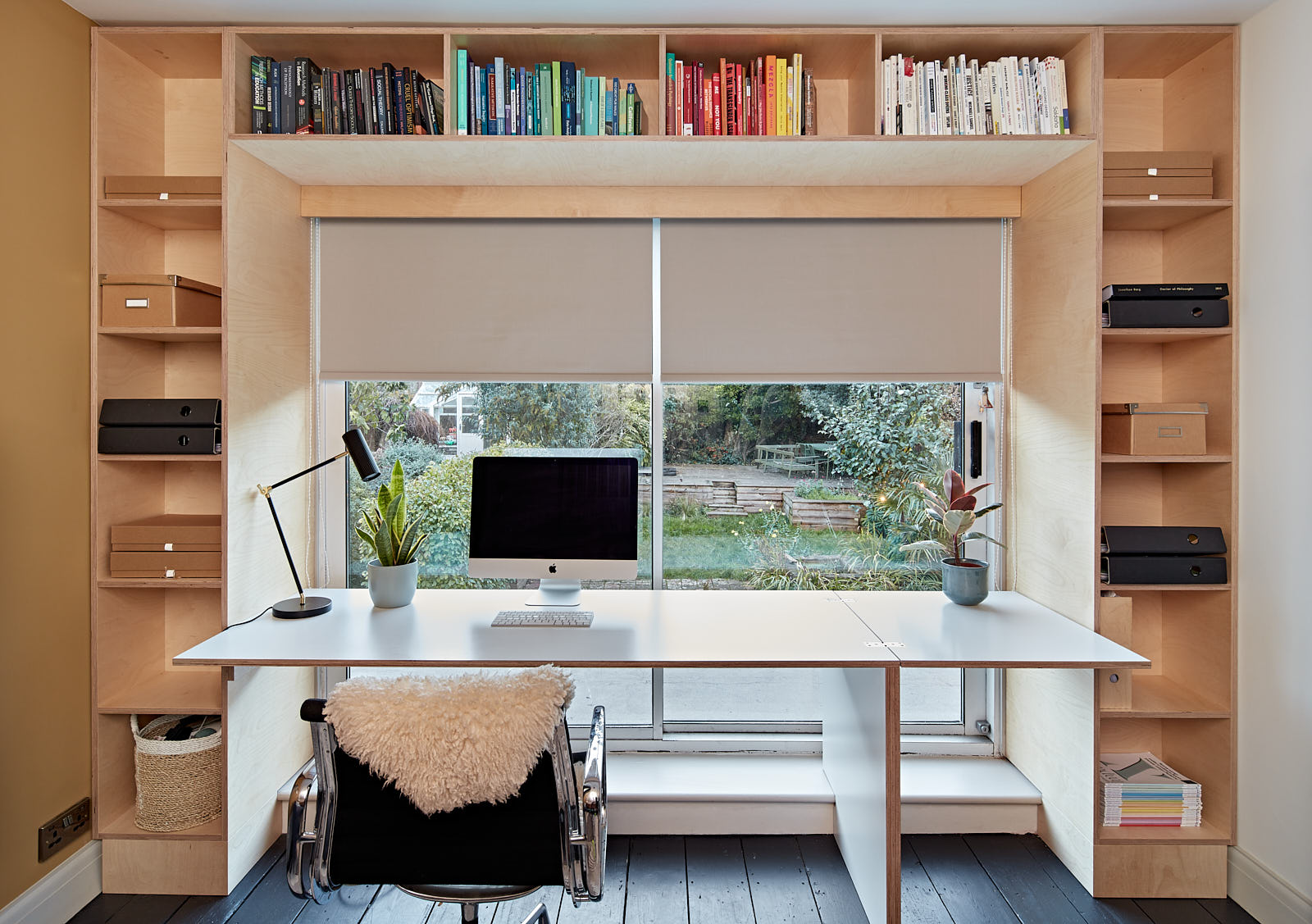 In this contemporary office space we designed and built a bespoke timber desk framed with perimeter shelving to conceal a hidden blind. Perfect for working from home, enjoying views towards the garden and access to the roof terrace on sunny days.