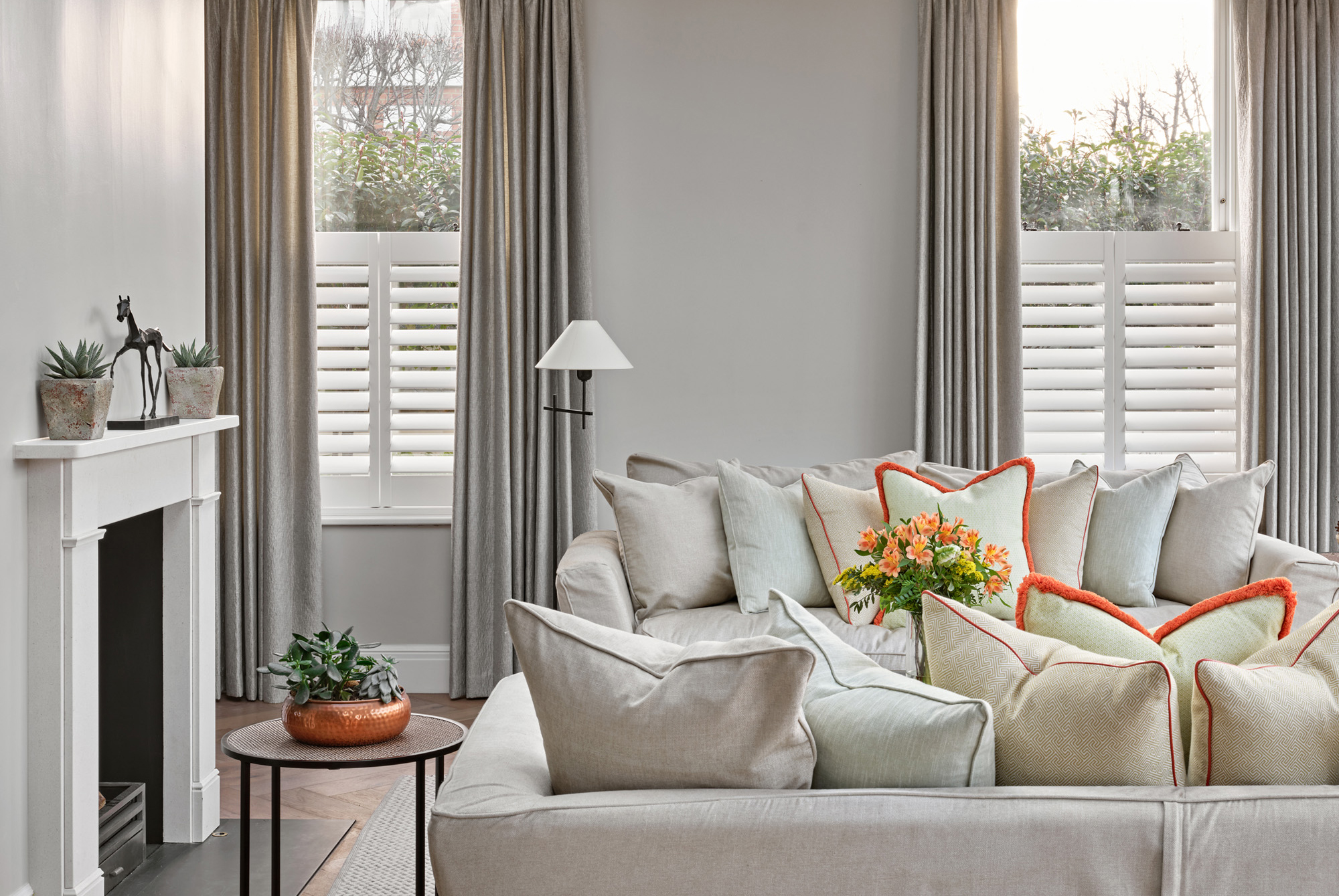 Bright and Airy Open Plan Living Room with Skylight – Luxury Barnes Home – A beautifully designed living area flooded with natural light from a large skylight, showcasing plush neutral furnishings, contemporary lighting, and floor-to-ceiling crittall windows that open onto a landscaped garden.