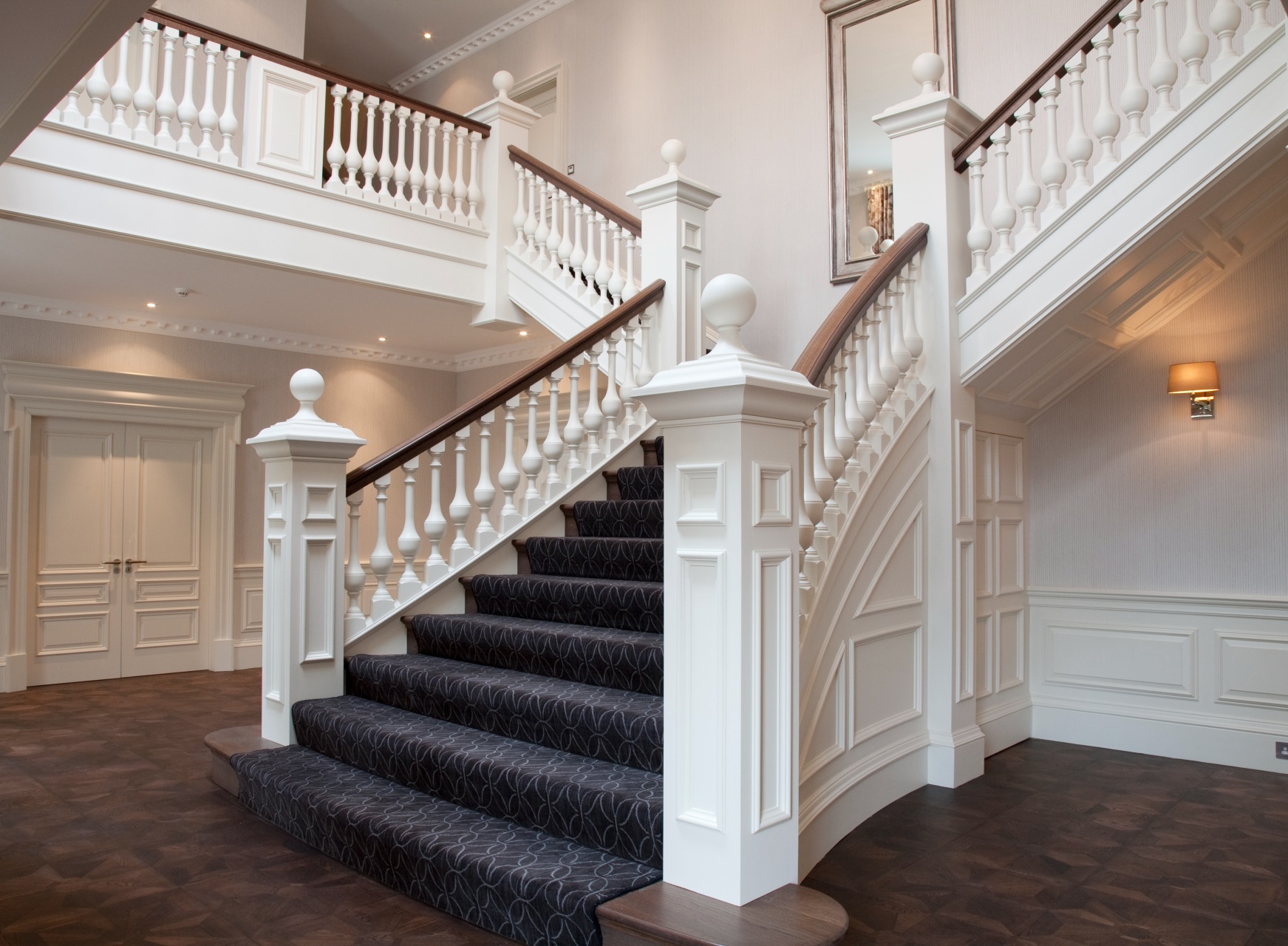 A grand white painted staircase with dark wooden handrail