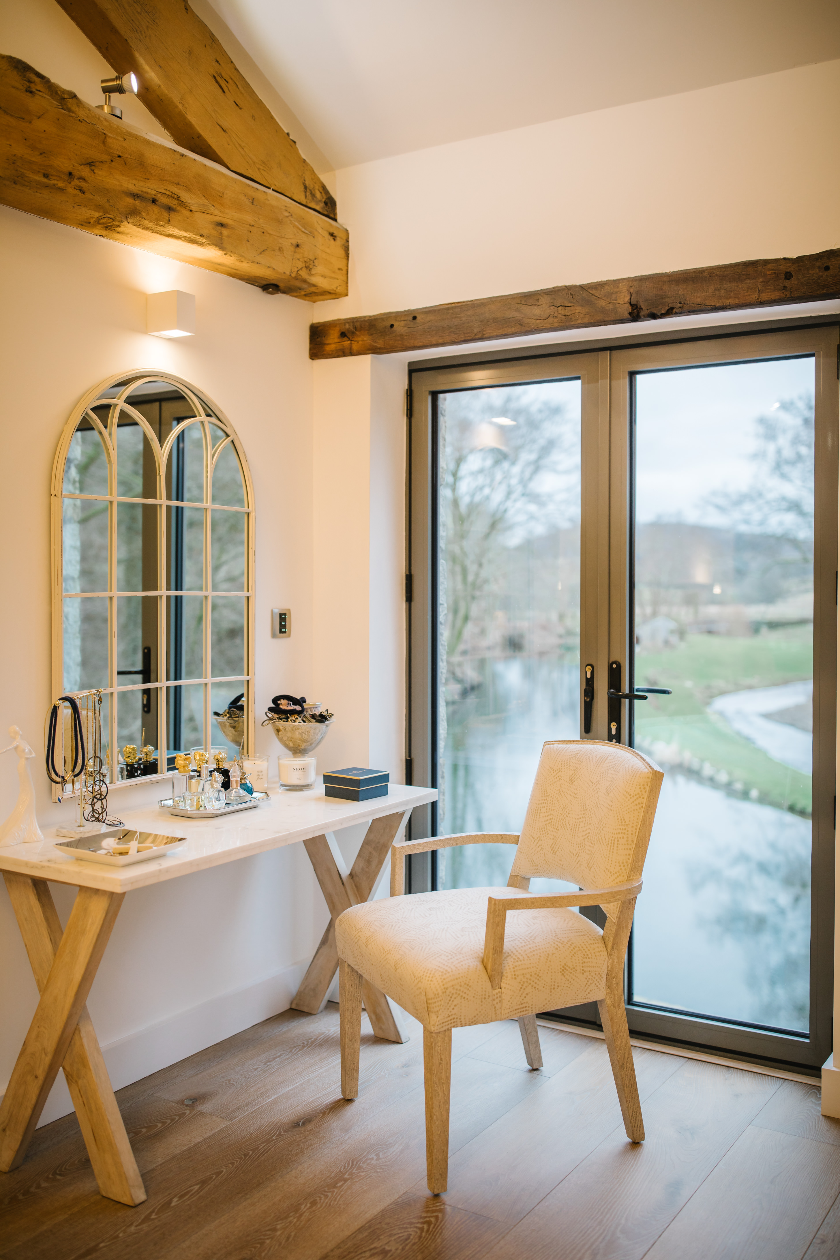 Light and bright dressing table area, with exposed beams, and view out to the millpond.