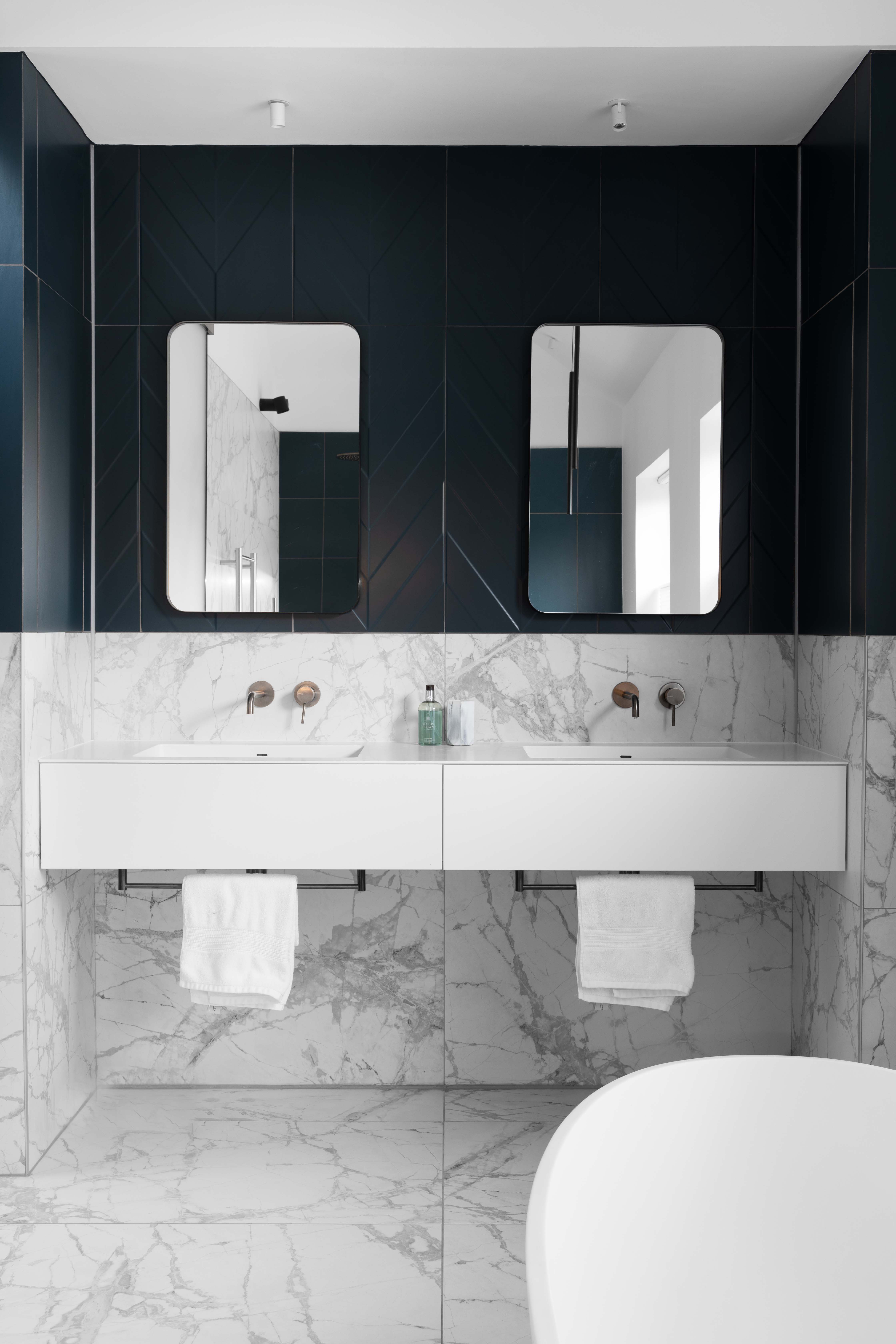 The master en-suite has a minimal luxury feel with a large freestanding bath, bespoke made double vanity unit and large format feature tiles.