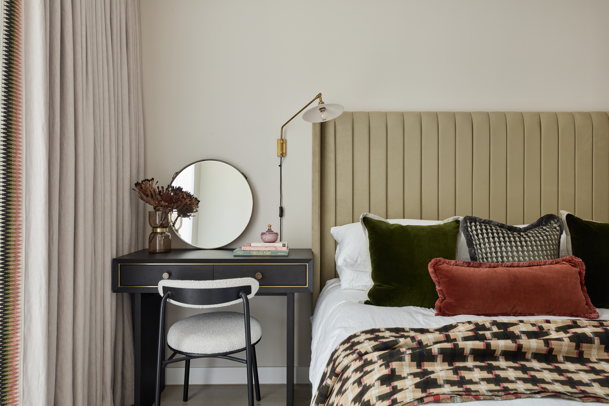 Elegant master bedroom at Triptych Bankside, a Southbank London apartment, featuring a green velvet headboard, plush cushions, and a sleek black dressing table.