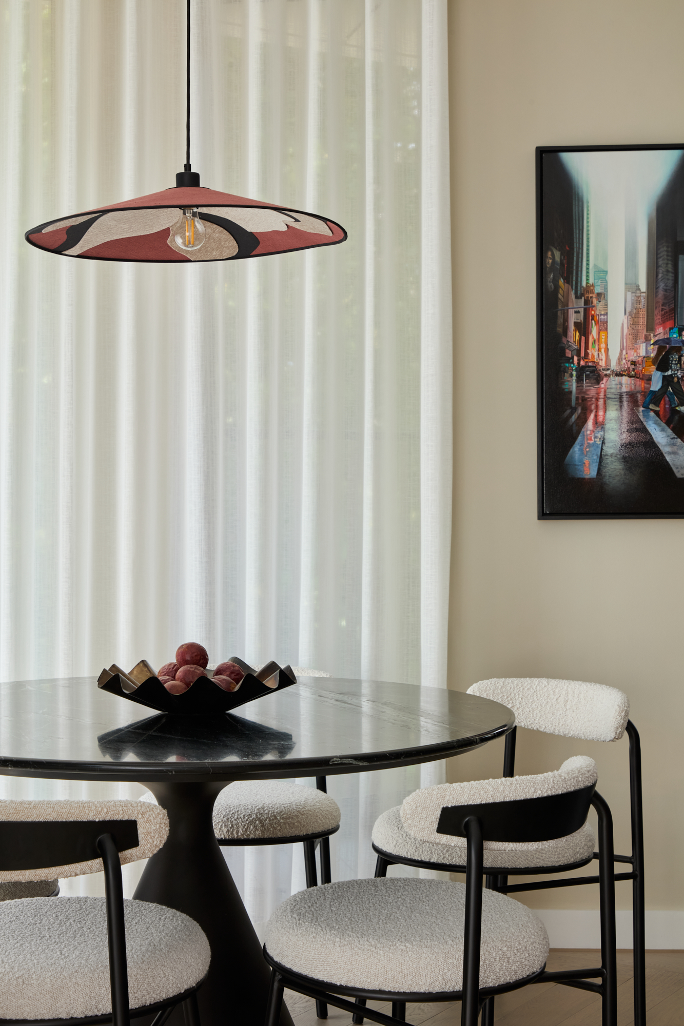 Luxury dining area in Triptych Bankside, a Southbank London apartment, featuring a round black marble table, boucle chairs, and a sculptural fabric pendant light.