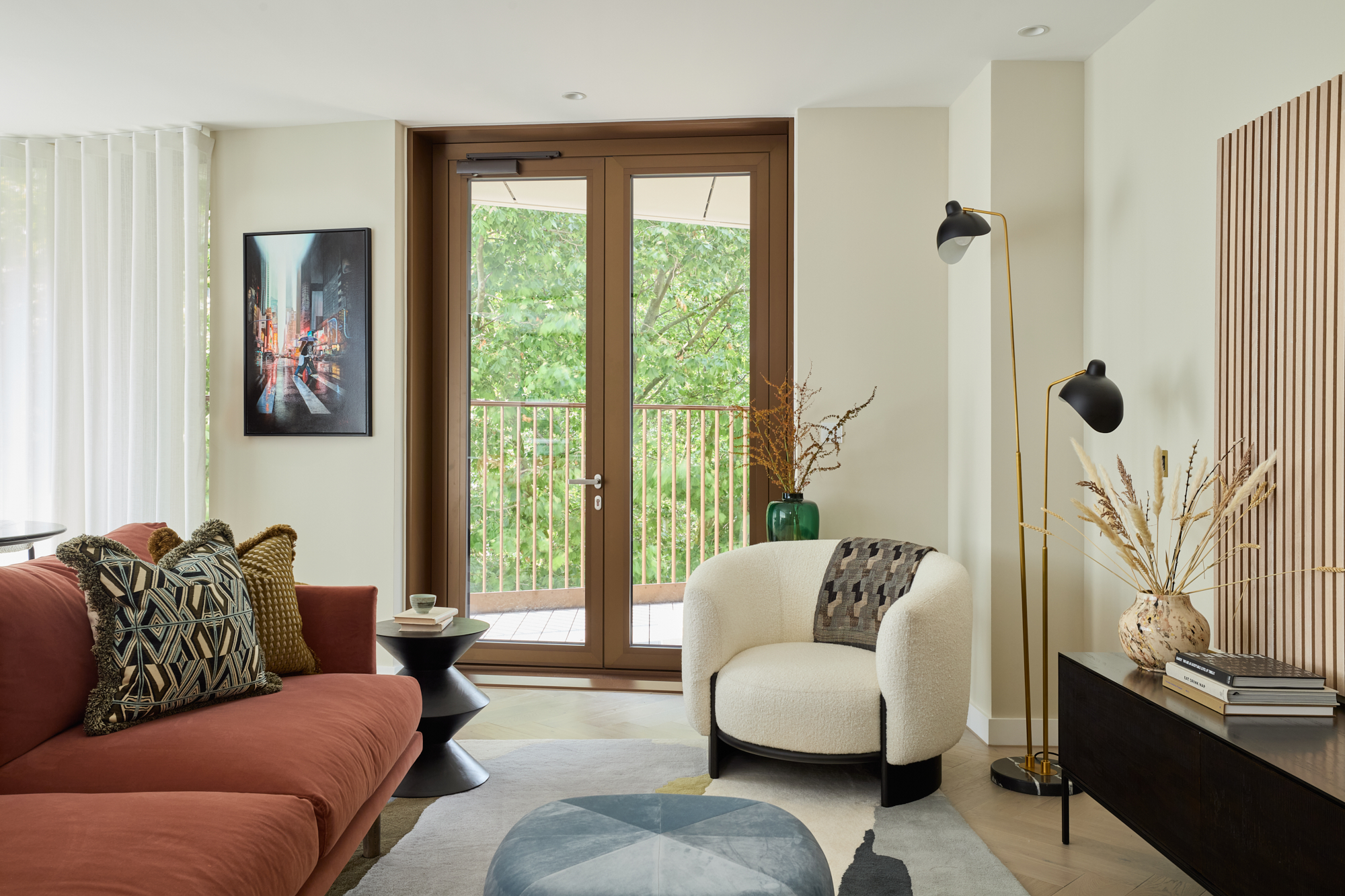 Stylish reading nook in a Triptych Bankside apartment featuring a boucle armchair, statement floor lamp, and a balcony with views over London’s Southbank.