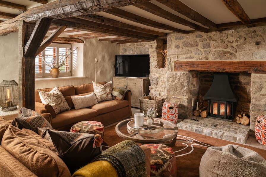 Cosy snug room with exposed beams, terracotta sofas and glass coffee table