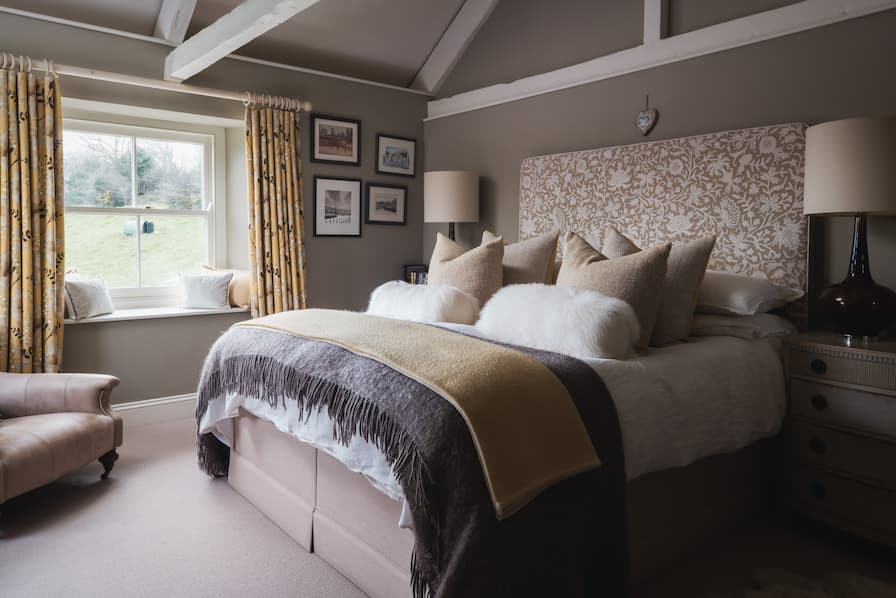 Cosy moorland bedroom with layered bedding and scatter cushions in earthy tones