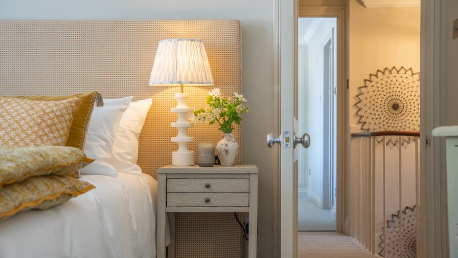 Sunny yellow bedroom with gingham headboard and statement white table lamp