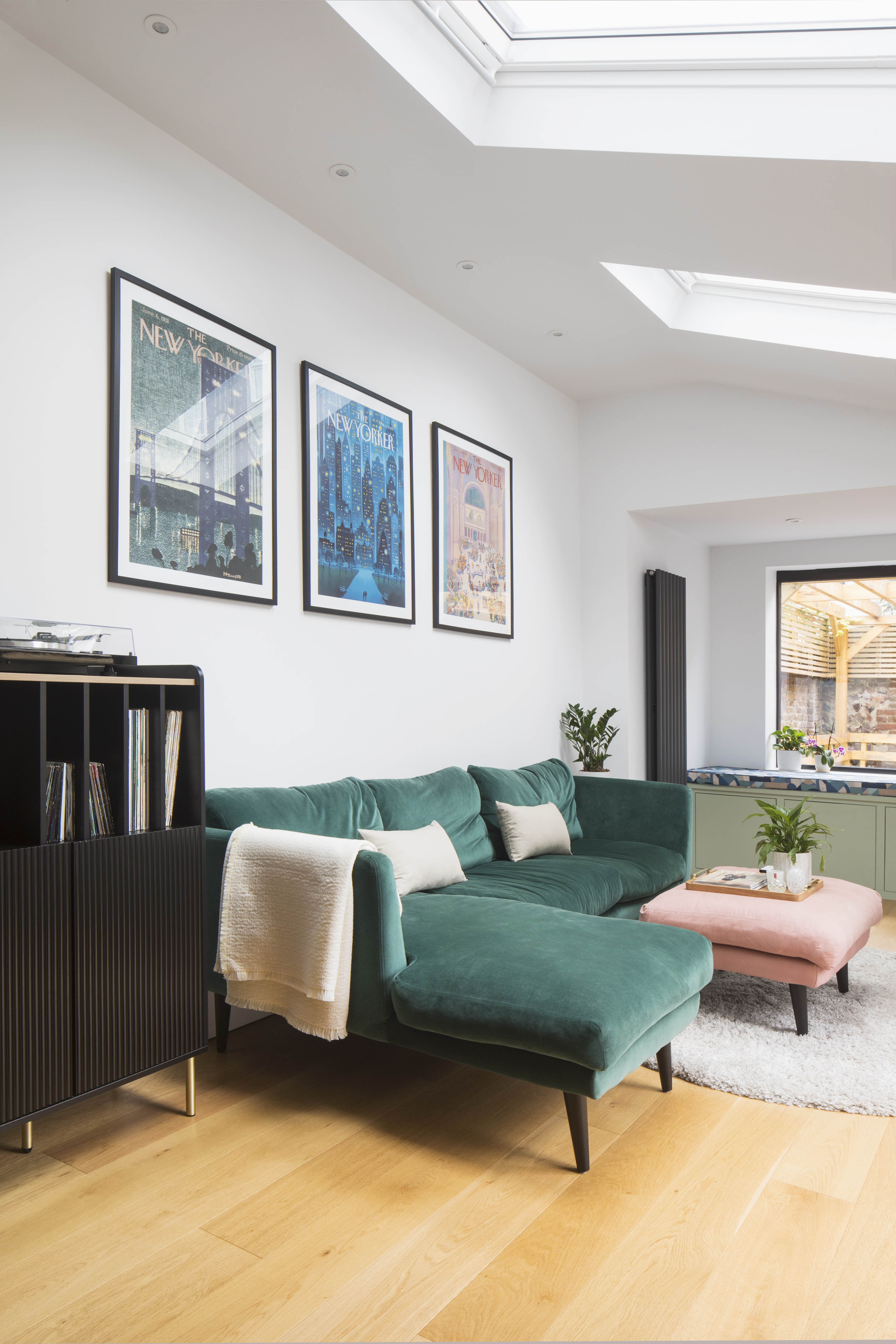 Snug area with L shape teal velvet sofa, pink footstool and green window seat