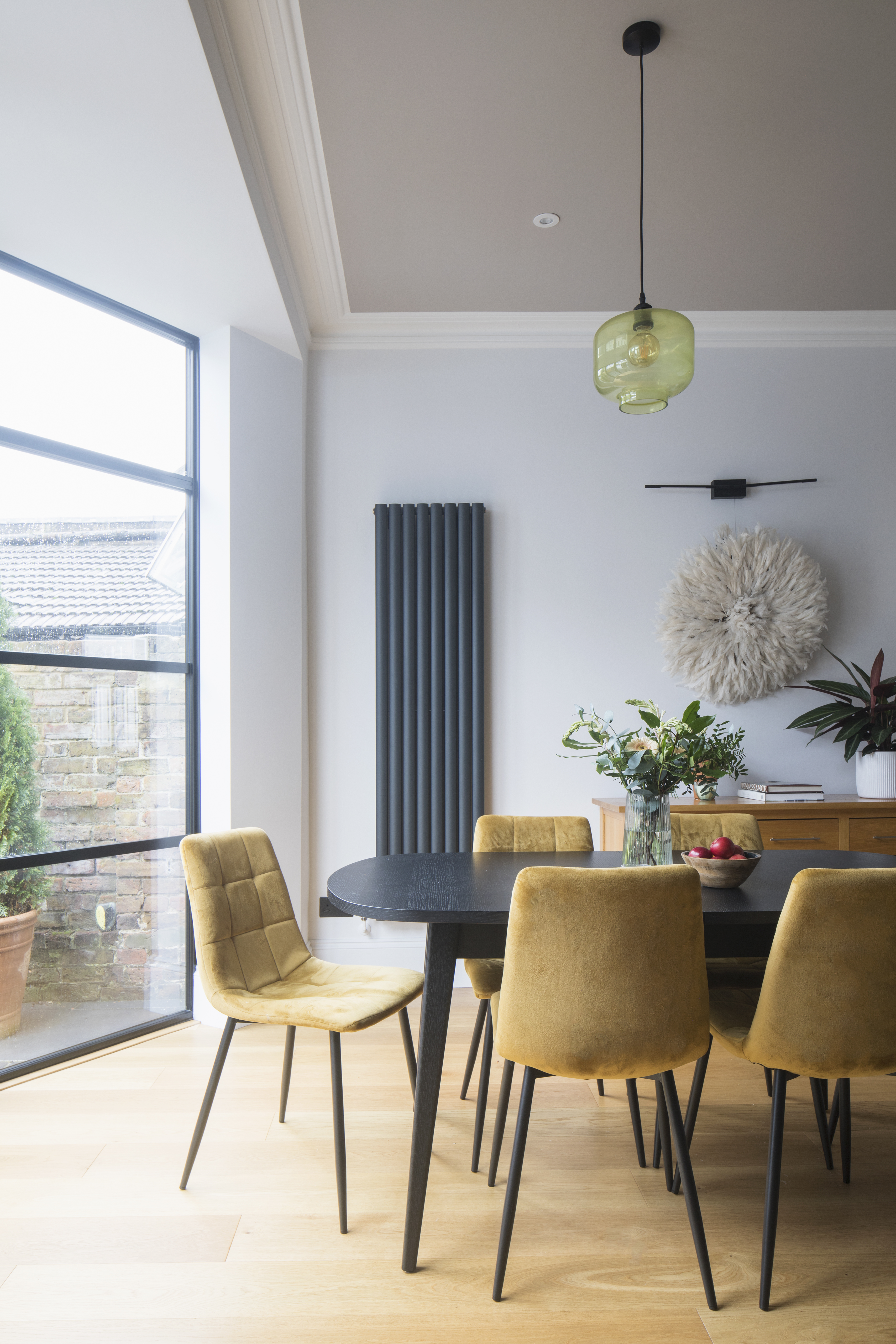 Black dining table with mustard chairs.  Black crittal doors