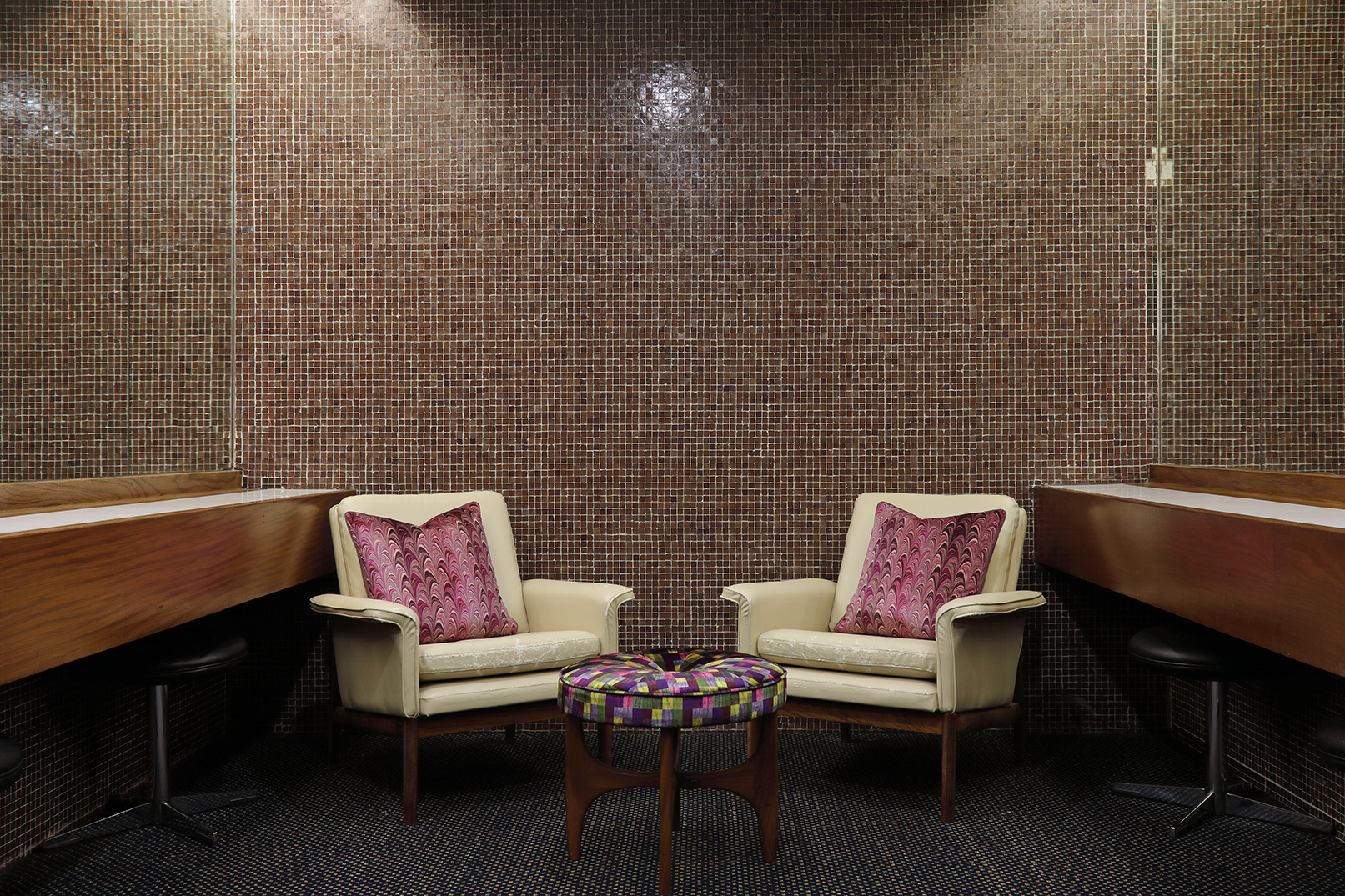 Susi Bellamy cushions and fabric covered footstool in the mosaic tiled ladies' powder room.