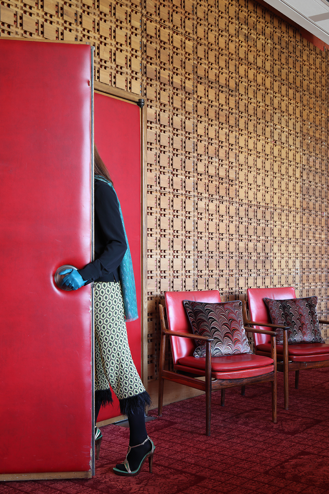 Woman walking through a doorway with 2 chairs beyond with Susi Bellamy cushions