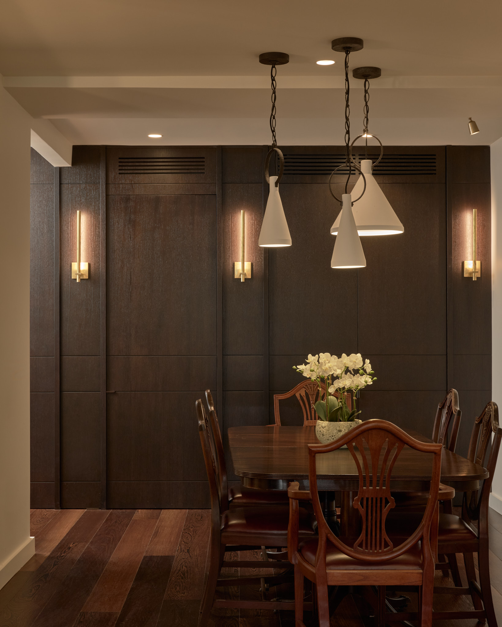 Antique dining table with plaster pendant lights.  Joinery wall with hidden job door to access bedrooms.