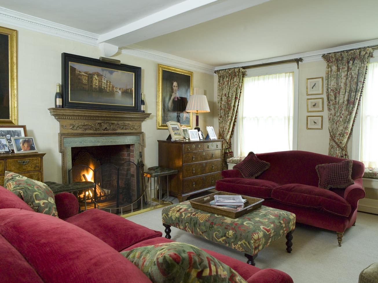 Gathered floral linen curtains lend a relaxed air to the country sitting room with its low ceiling and large family portraits.