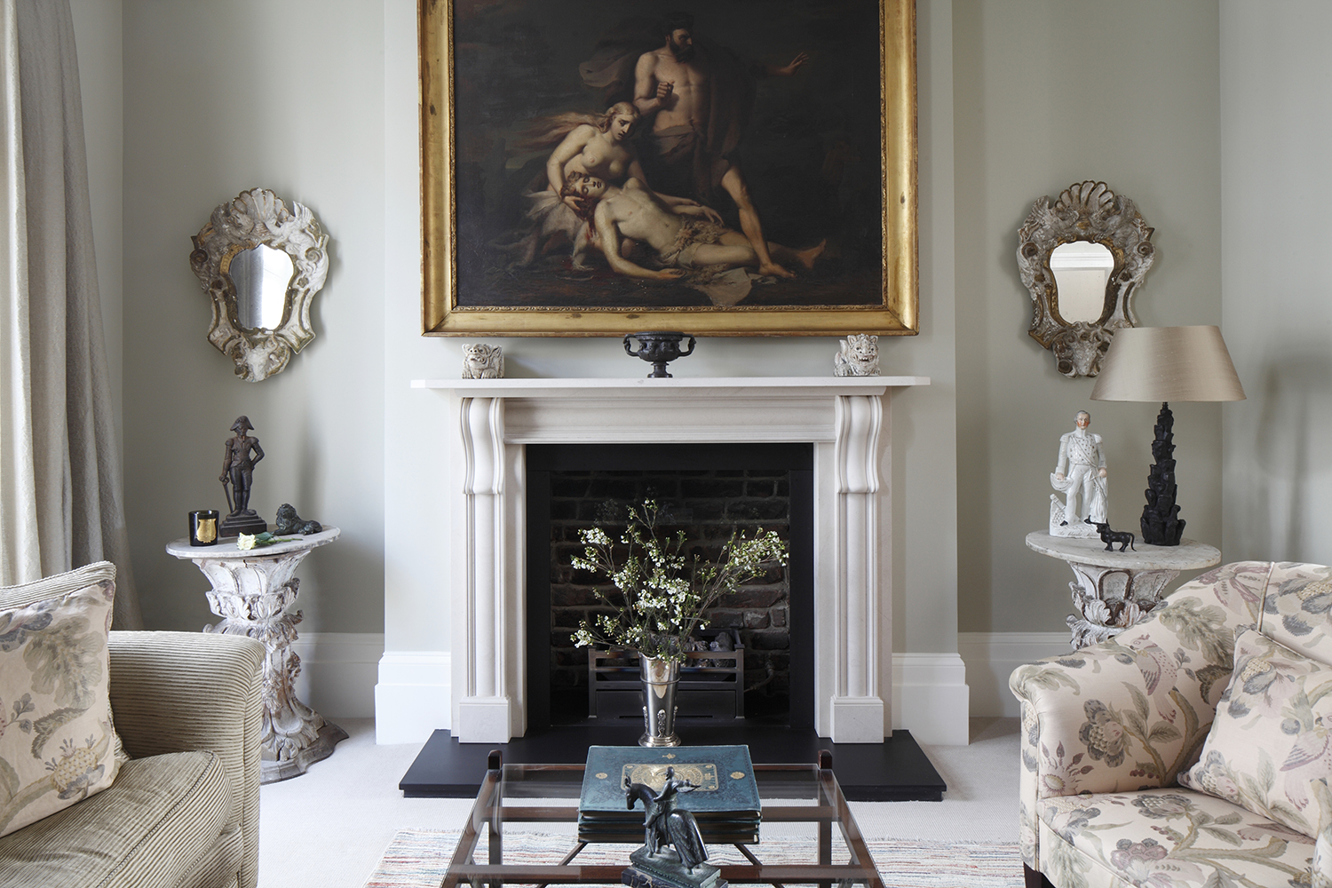 Soft eau de nil painted walls are the backdrop for faded floral linens, a striking work of art and a pair of vintage Venetian mirrors.