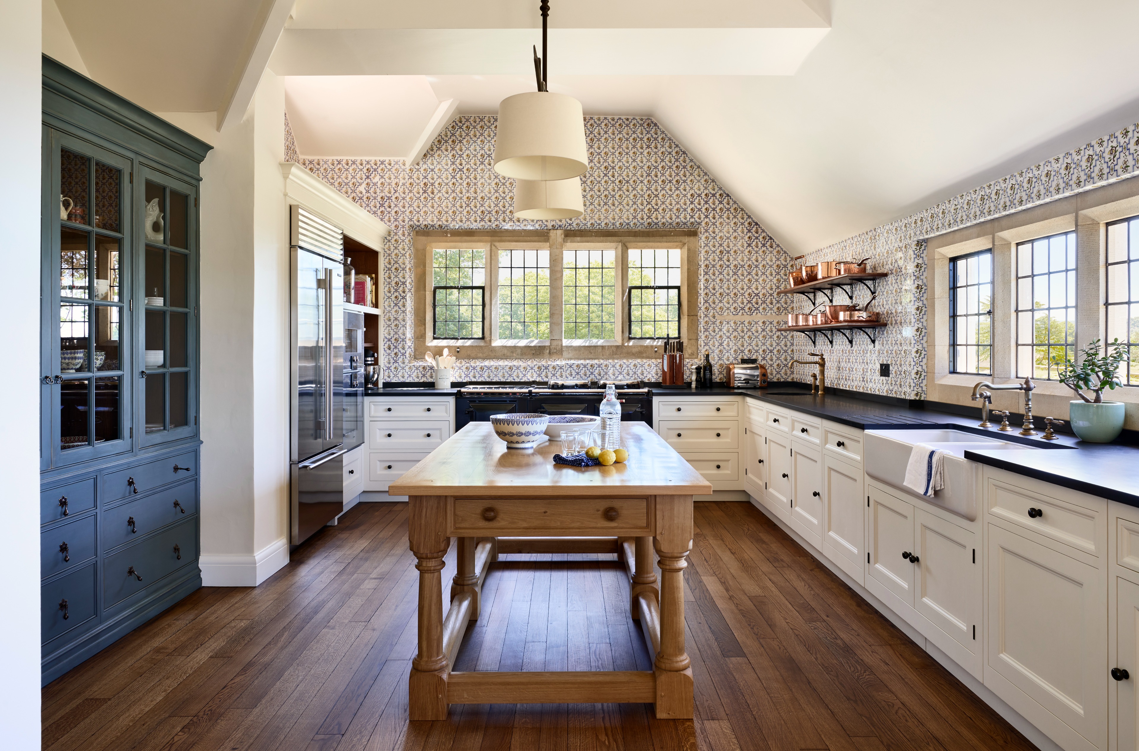 A large open plan kitchen with Delft wall tiles & white kitchen cabinets with Welsh black slate worktops