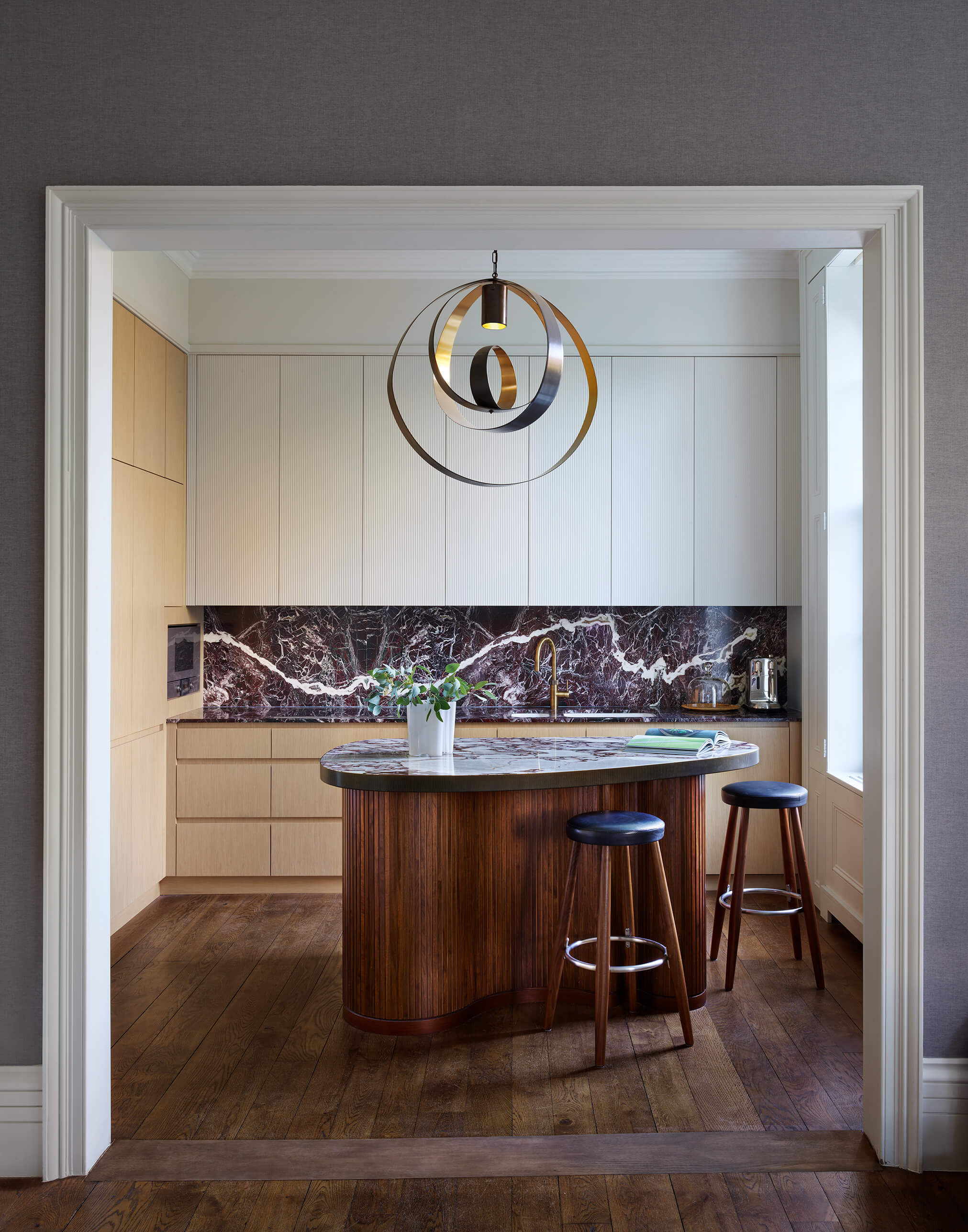 A kitchen wth a walnut slatted island unit, white painted wall units and oak veneer base and tall units 