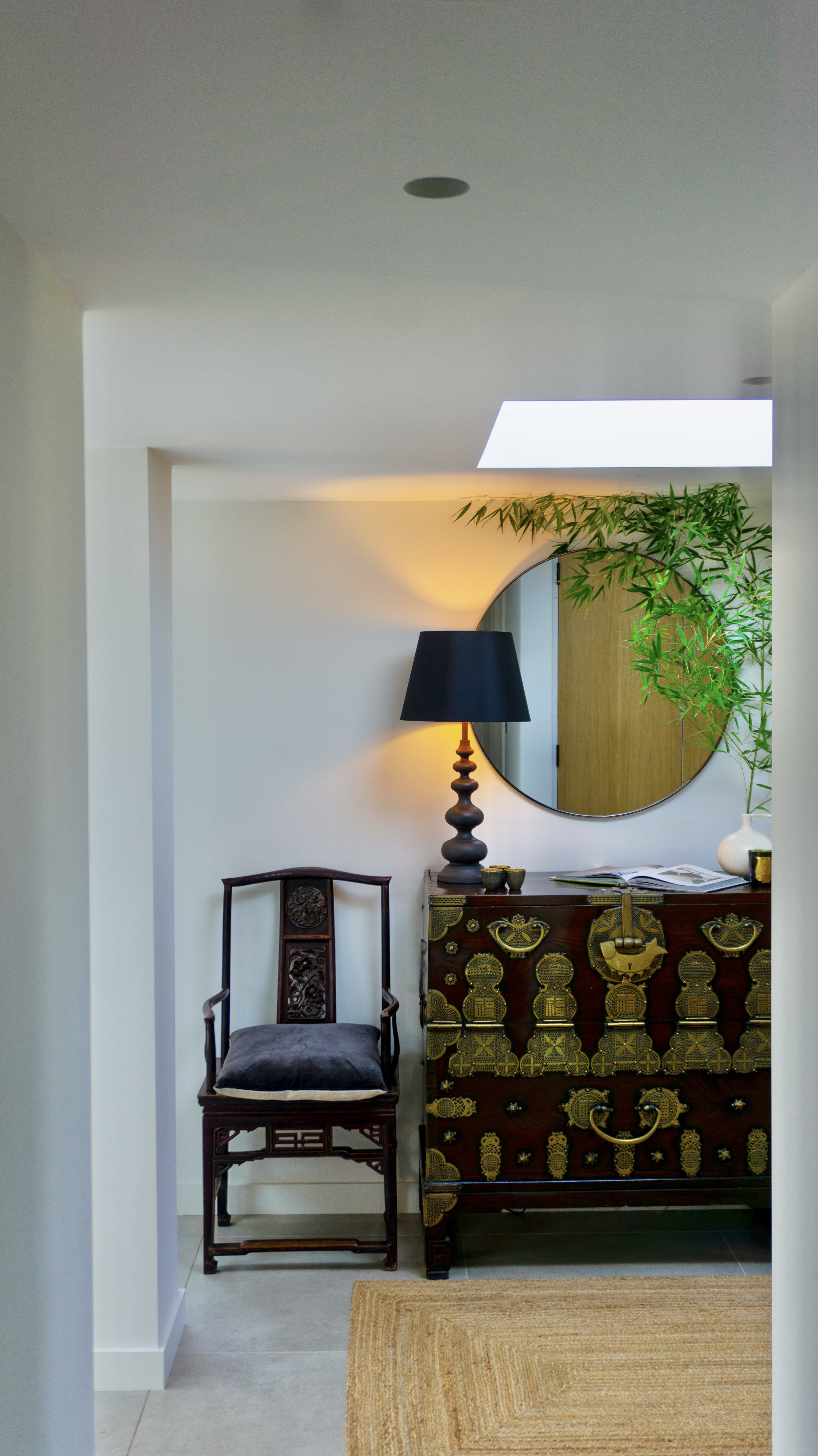 Modern hallway with Korean chest, round mirror and black lamp