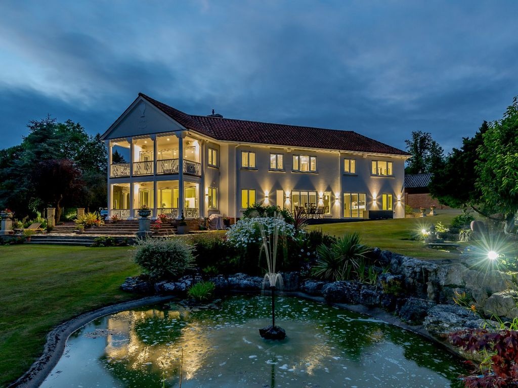 Shows inviting exterior of home at dusk, with lights on.