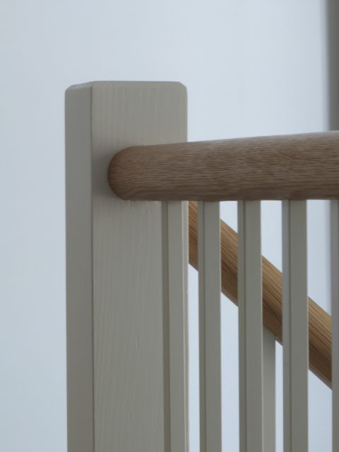 Oak handrail and powder coated metal balusters in simple Shaker style on cottage staircase