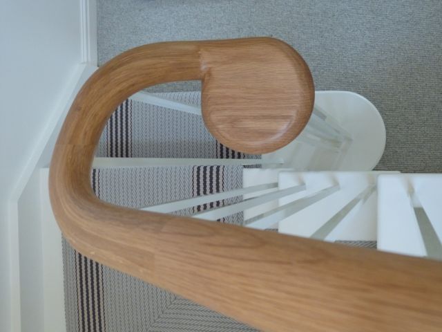 Oak handrail and powder coated metal balusters in simple Shaker style on cottage staircase