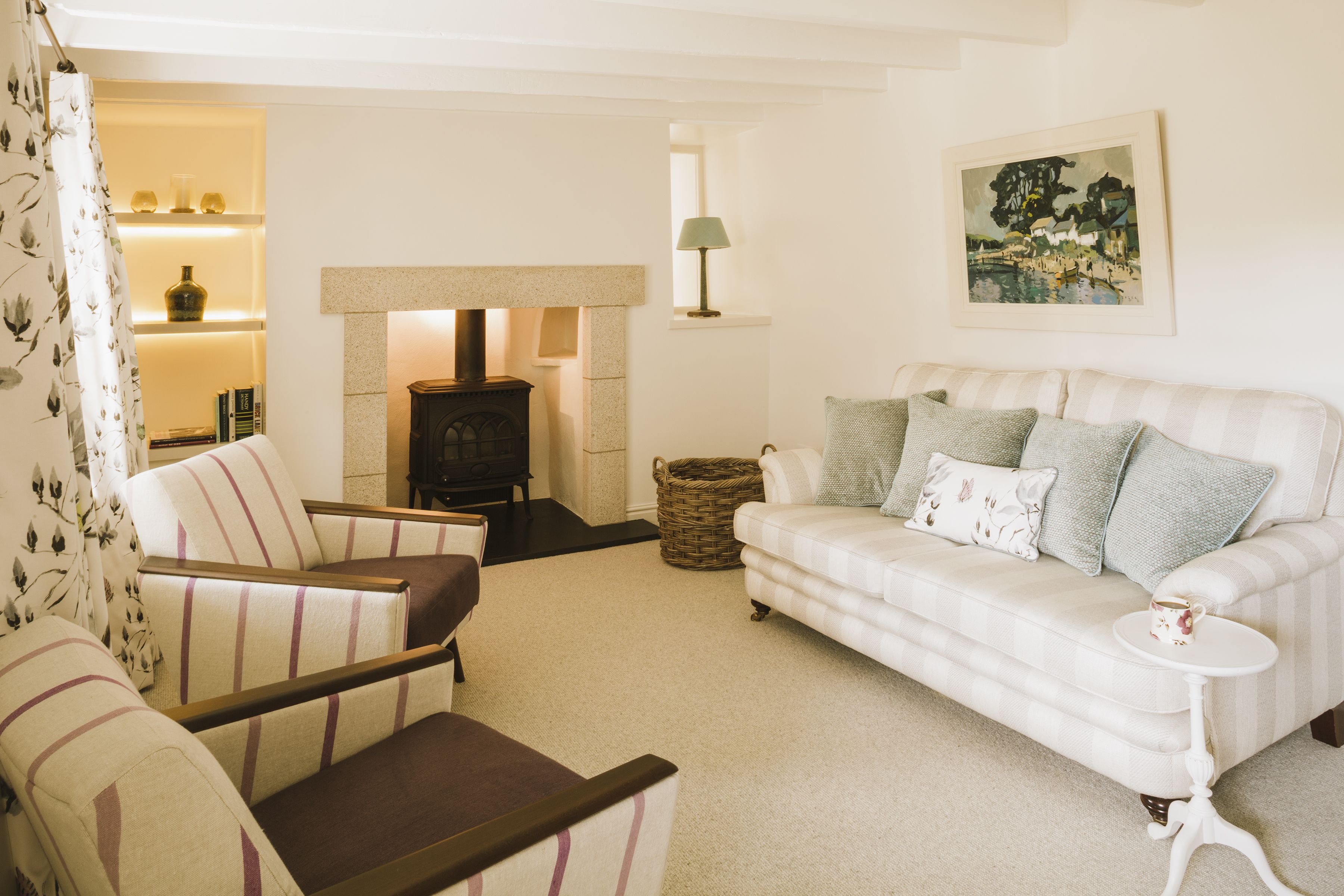 Cottage sitting room with granite fire surround, grey carpet, Designers Guild curtains and backlit floating shelves