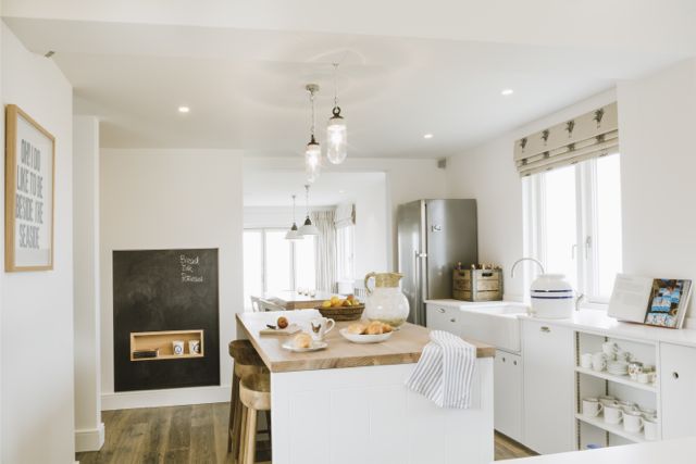 Traditional white kitchen in coastal home.  Island unit with wooden worktop and dark wood floor