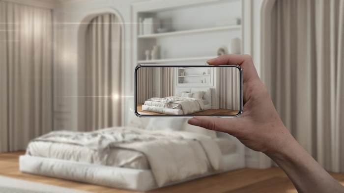 a person using a smartphone to take a photo of a bedroom