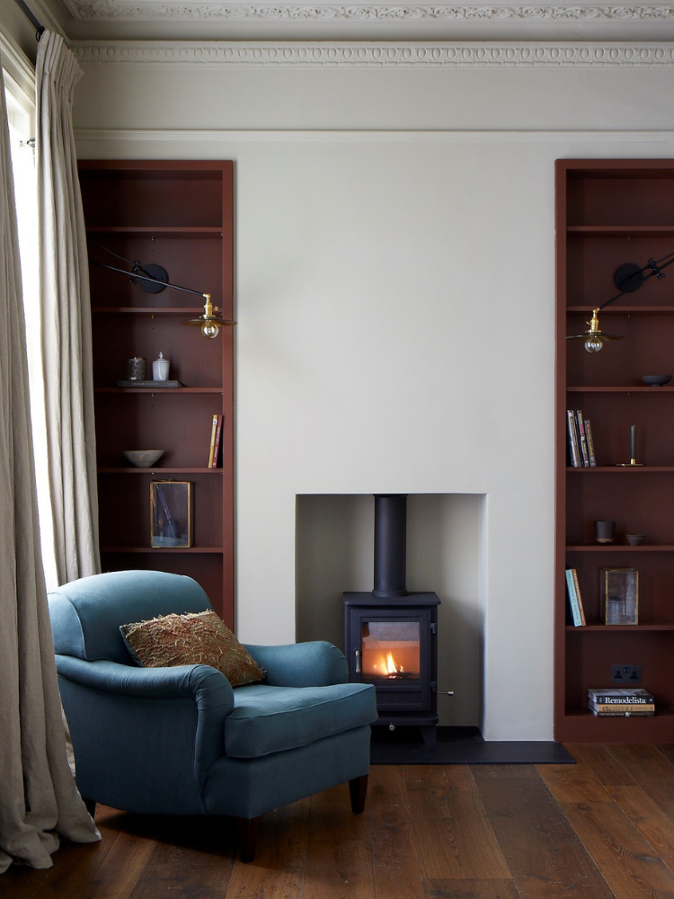 Front room interior with smoked oak floor and woodburning stove , featuring a chair upholstered in blue linen.