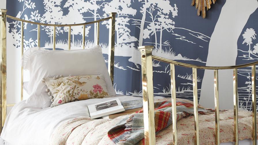 Romantic brass bed against a blue and white pictorial wallpaper