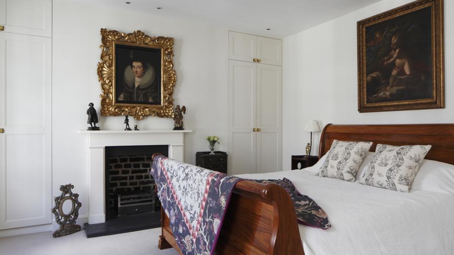 A calm off-white bedroom styled with a coloured vintage bed throw.