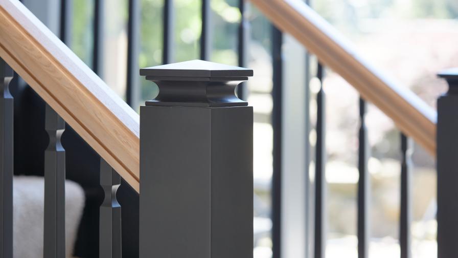 A detail view of a classic contemporary style staircase painted in dark grey with a handrail in natural oak.