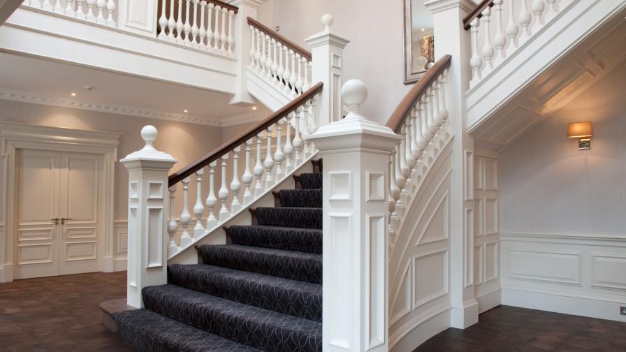 A grand white painted staircase with dark wooden handrail