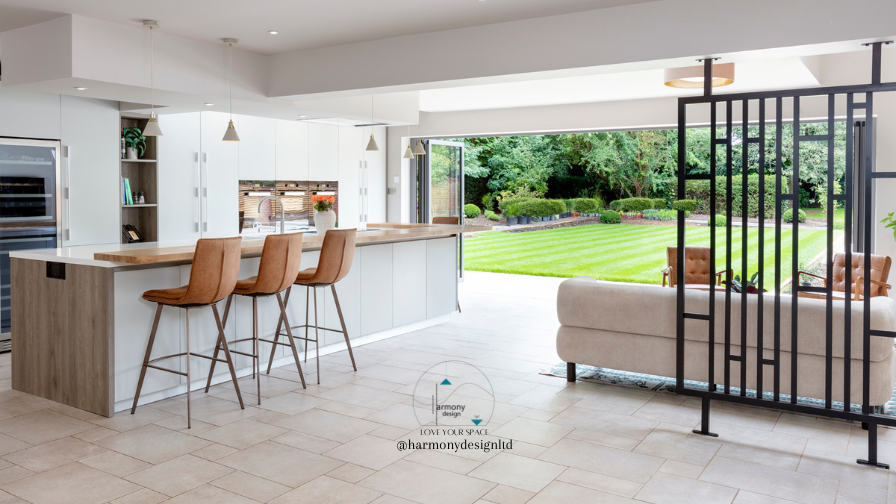 Kitchen overlooking the garden with white cabinets and wood breakfast bar. black screen divider seperating the snug.