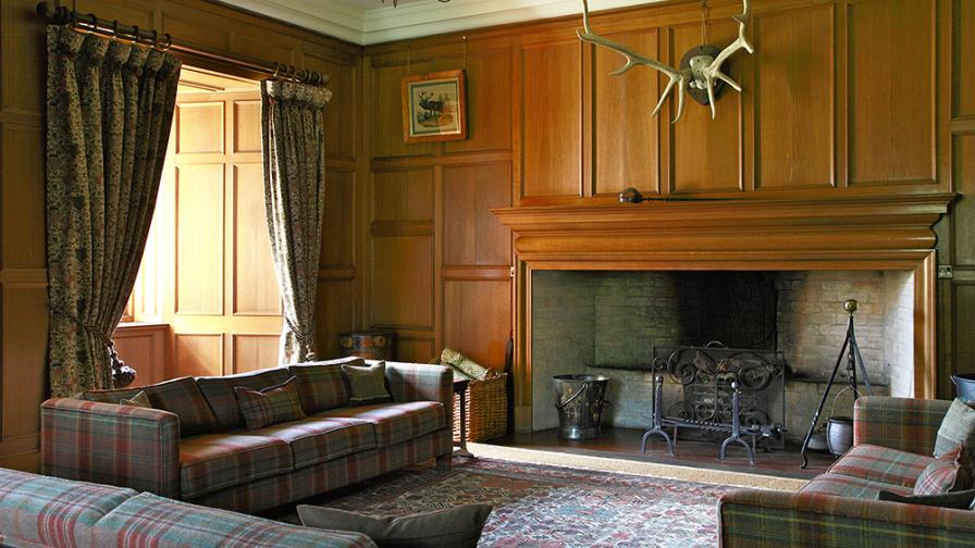 Tapestry curtains and plaid upholstery are the perfect combination with the antique fumed oak paneling of this sixteenth century room.