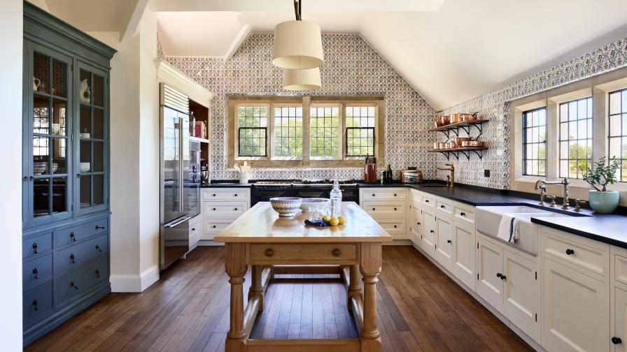 A large open plan kitchen with Delft wall tiles & white kitchen cabinets with Welsh black slate worktops