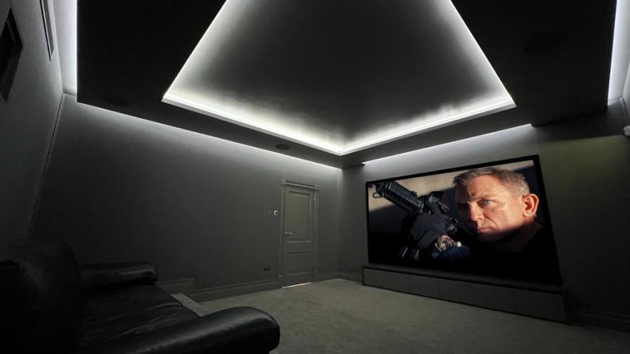 Small home cinema room with projector, screen and seating.