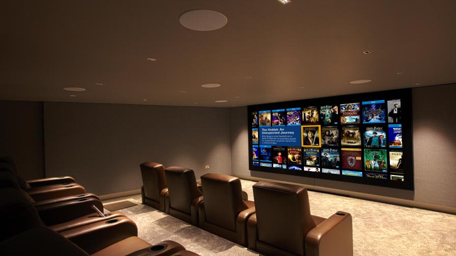 Home cinema, with leather seating and large screen showing Kaleidescape image.